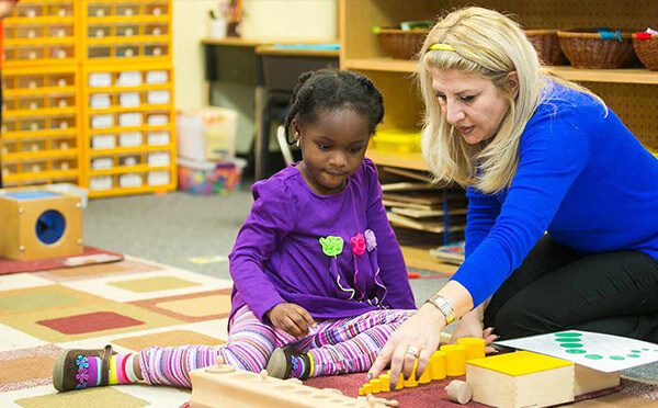 Teacher showing child part of the Montessori curriculum.